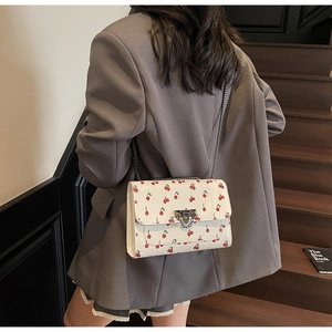 Vue arrière du modèle portant un sac à chaîne cerise sur un escalier en bois