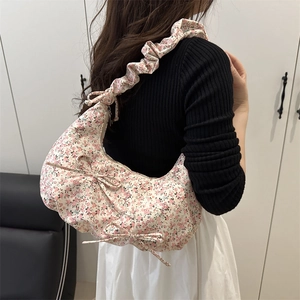 Floral pleated hobo bag with pink bows and ruffled strap shown on a female model