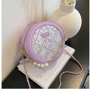 Detail of round purple crossbody bag with geometric embroidery and pearl accents