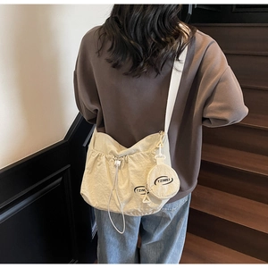 Detail einer beigen Beuteltasche mit Kordelzug und einer kleinen runden Münztasche
