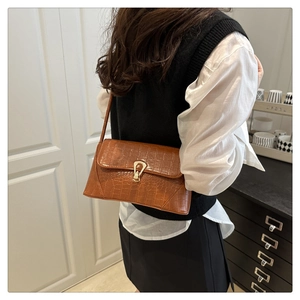 Detailed close-up of brown crocodile pattern shoulder bag with golden horseshoe lock