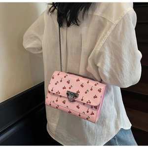 Vue de dos d'un mannequin portant un sac rose imprimé cerise avec bandoulière chaîne