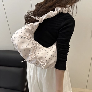Floral crossbody cloud bag with bow accents and pleated strap on female model
