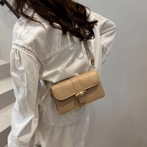 Sac bandoulière beige à texture croco et fermoir bambou doré porté par un modèle