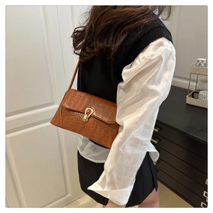 Brown crocodile embossed faux leather crossbody bag with a gold metal U-shaped buckle