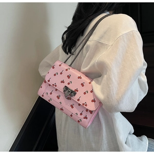 Vue détaillée du sac rose à imprimé cerise avec bandoulière chaîne et fermoir en métal