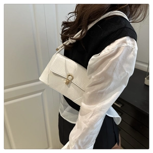 Detail of white crocodile pattern shoulder bag with elegant golden metal buckle closure