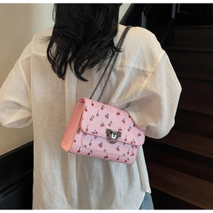 Détail du sac bandoulière rose à motif cerise avec chaîne argentée et fermoir pivotant