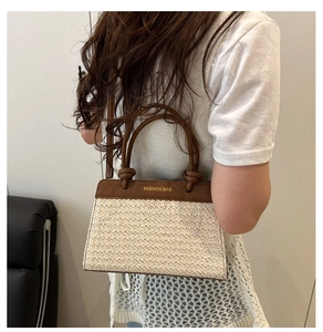 Detail of woven straw tote bag with brown leather handles and FASHION BAG text