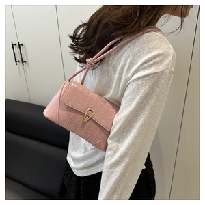 Detail of pink crocodile embossed faux leather shoulder bag with gold metal lock closure