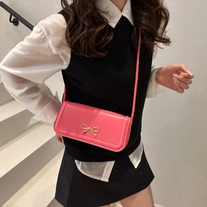 Trendige pinke Baguette-Tasche aus Leder mit goldener Schleifenschnalle am Modell