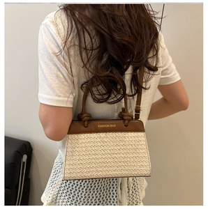 Detail of straw woven crossbody bag with brown leather trim worn by a model