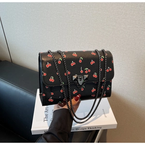 Détail du sac à main imprimé cerise avec bandoulière chaîne et fermoir pivotant