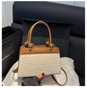 Detail of woven straw tote bag with brown leather trim and knotted handle detail