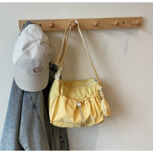 Detail der gelben Nylon-Umhängetasche mit Mini-Beutel an einem Holzhaken