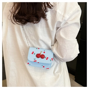 Detailansicht der hellblauen Mini-Tasche mit Kirschprint und 3D-Kirschschnalle am Modell