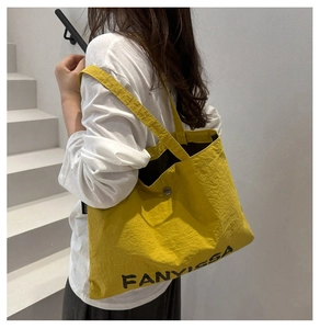 Detail of yellow nylon tote bag with pleated texture and FANYISSA logo branding