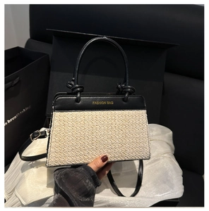 Detail of contrast stitch handbag featuring woven texture and gold fashion lettering