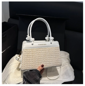 Detail of a straw patchwork crossbody bag featuring a leather top and knotted handle