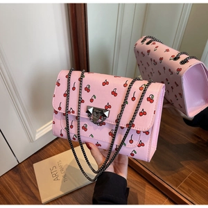 Détail d'un sac à bandoulière rose à imprimé cerise avec une bandoulière en chaîne