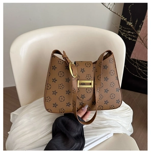 Dettaglio borsa a tracolla marrone con motivo monogramma e fibbia in metallo dorato