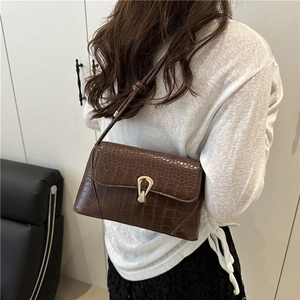 Brown crocodile pattern crossbody bag with a gold lock buckle shown on model