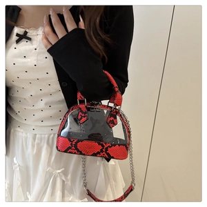 Dettaglio dei bordi in pelle di serpente rossa e borsa a conchiglia in PVC trasparente