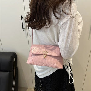 Pink crocodile pattern shoulder bag with a stylish gold clasp shown on a model