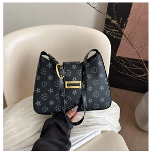 Dettaglio borsa a spalla nera monogram con fibbia dorata e motivi floreali a stella
