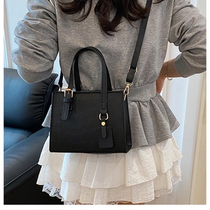Model wearing a black crocodile embossed small square crossbody bag with gold hardware