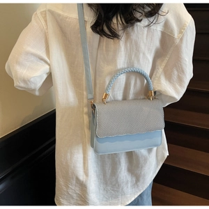 Détail du sac à bandoulière bleu ciel avec poignée tressée et rabat festonné ondulé