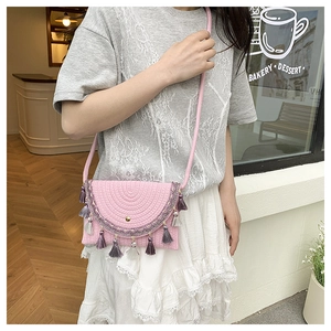 Detail of pink woven straw crossbody bag with colorful tassels and geometric embroidery