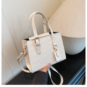 Close-up of white crocodile pattern shoulder bag with metal buckles and stylish handle
