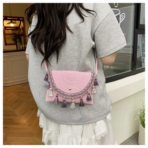 Detail of pink woven saddle bag with multi-colored tassels and golden metal buckle