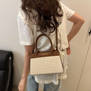 Minimalist straw patchwork shoulder bag with brown leather handles and adjustable strap