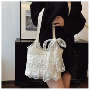 Detail of elegant cream lace tote bag featuring intricate floral patterns and a large bow