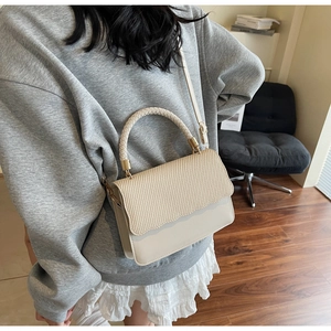 Détail d'un sac bandoulière beige avec texture tissée et mélange de matières lisses