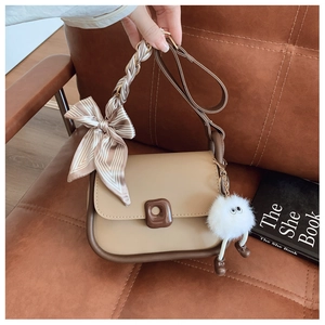 Detail of a chic two-tone crossbody bag with a striped silk scarf and plush charm
