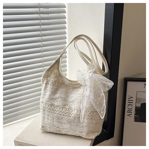 Detail of white lace shoulder bag with intricate floral patterns and ribbon decoration