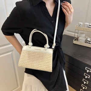 Minimalist white leather and straw patchwork crossbody bag with gold text and top handles