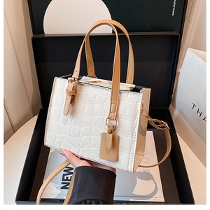 Detail of white crocodile embossed small square bag with brown handle in a gift box