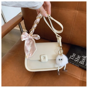 Detail of cream white crossbody bag with silk scarf handle and plush monster charm