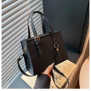 Detailed view of black croc-effect texture on a structured small square handbag