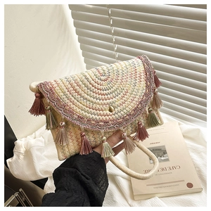 Close-up of woven straw handbag with colorful embroidery and bohemian fringe tassels
