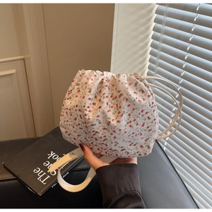 Detail of floral drawstring bucket bag with pink flower pattern and white canvas strap