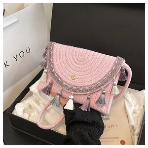Detail of pink hand-woven saddle bag with colorful tassels and metallic clasp inside a gift box