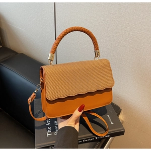 Détail du rabat en paille tressée et de l'anse ronde de ce sac à bandoulière orange
