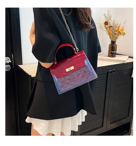 Detail of burgundy crocodile-embossed and blue PVC handbag with golden turn-lock closure