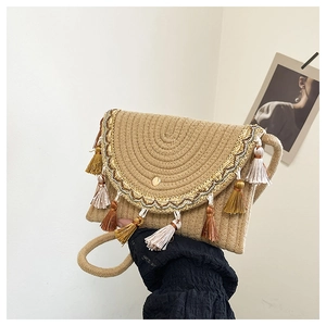Detail showing the straw woven texture, colorful fringe trim, and gold snap of the bag
