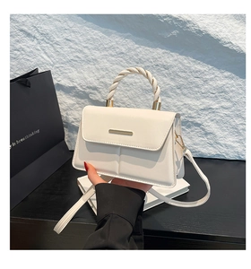 Détail d'un sac à main en cuir crème avec poignée tressée et fermoir en métal doré